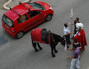 Il cavaliere a terra non soccorre alla stanchezza del cavallo di razza. Passa "distrattamente" un'autovettura di razza, carica come un mulo da soma.
